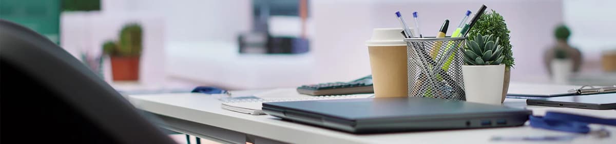 Modern office desk setup with laptop, stationery, coffee, and plant at Prozensoft Technologies